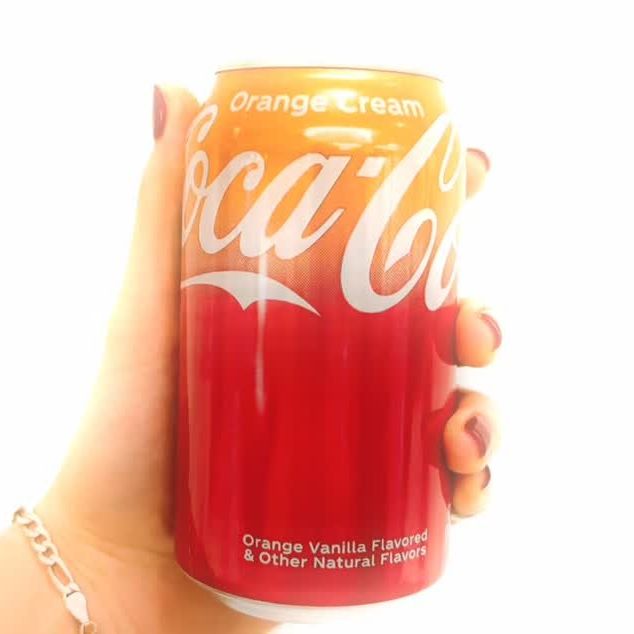 Une canette de Coca-Cola Orange Cream tenue à la main